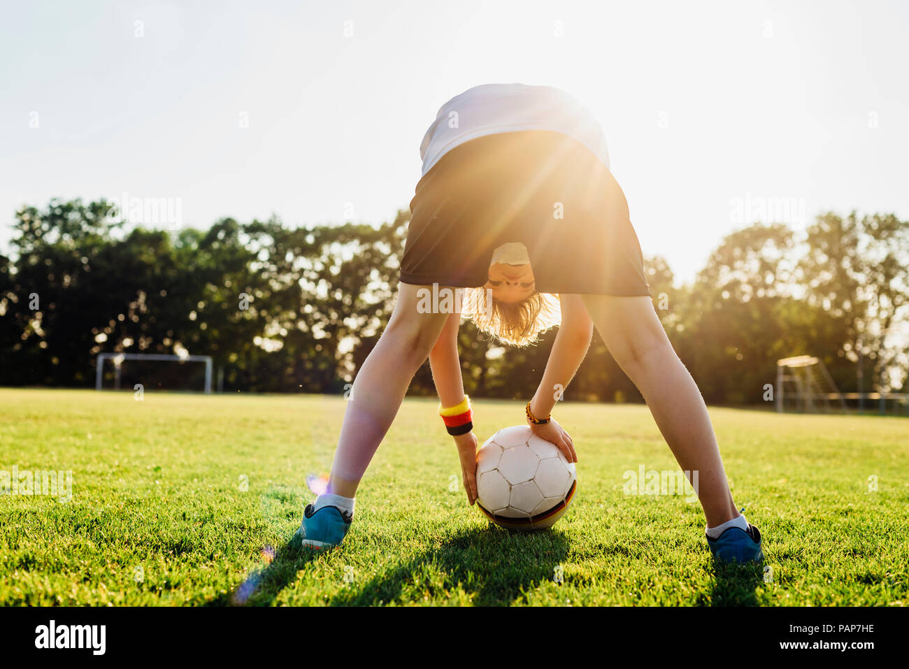 Boy on soccer field, bending over, looking through his legs Stock Photo