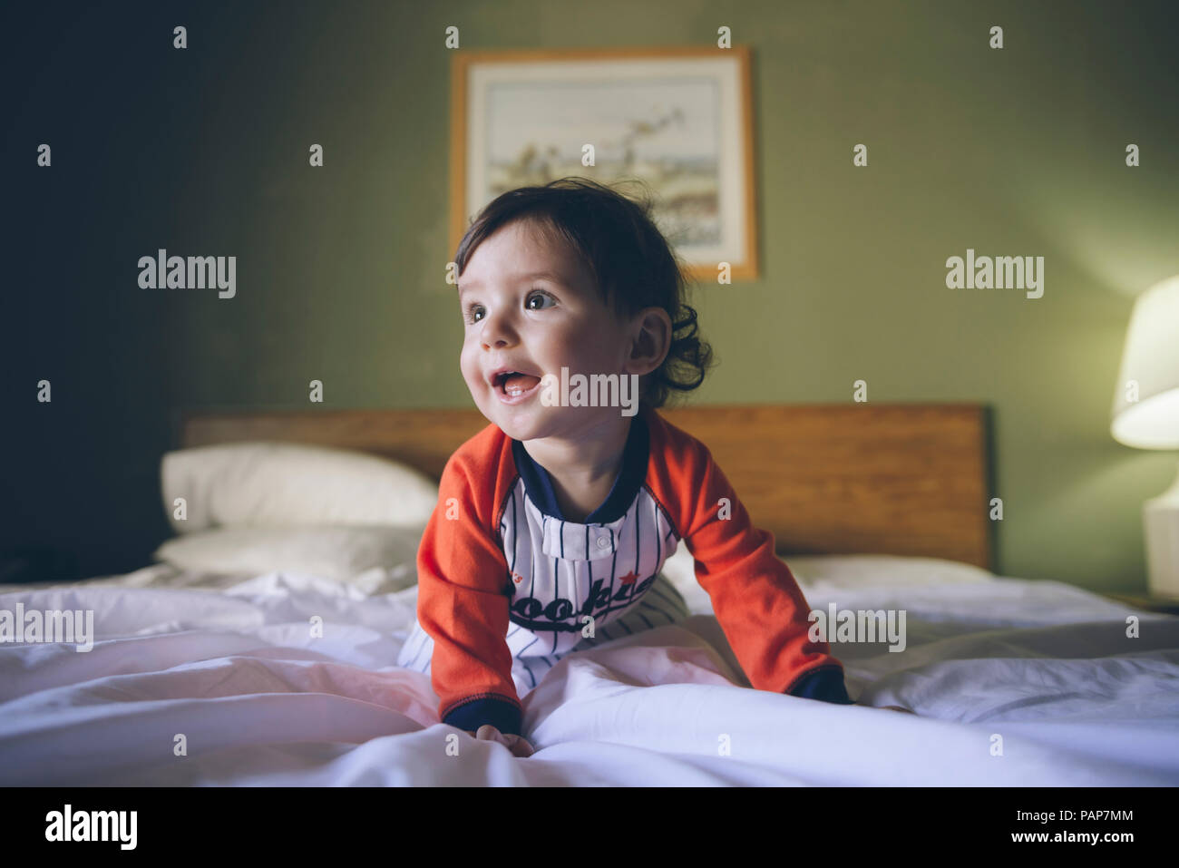 Portrait of baby girl wearing jumpsuit crawling on bed Stock Photo