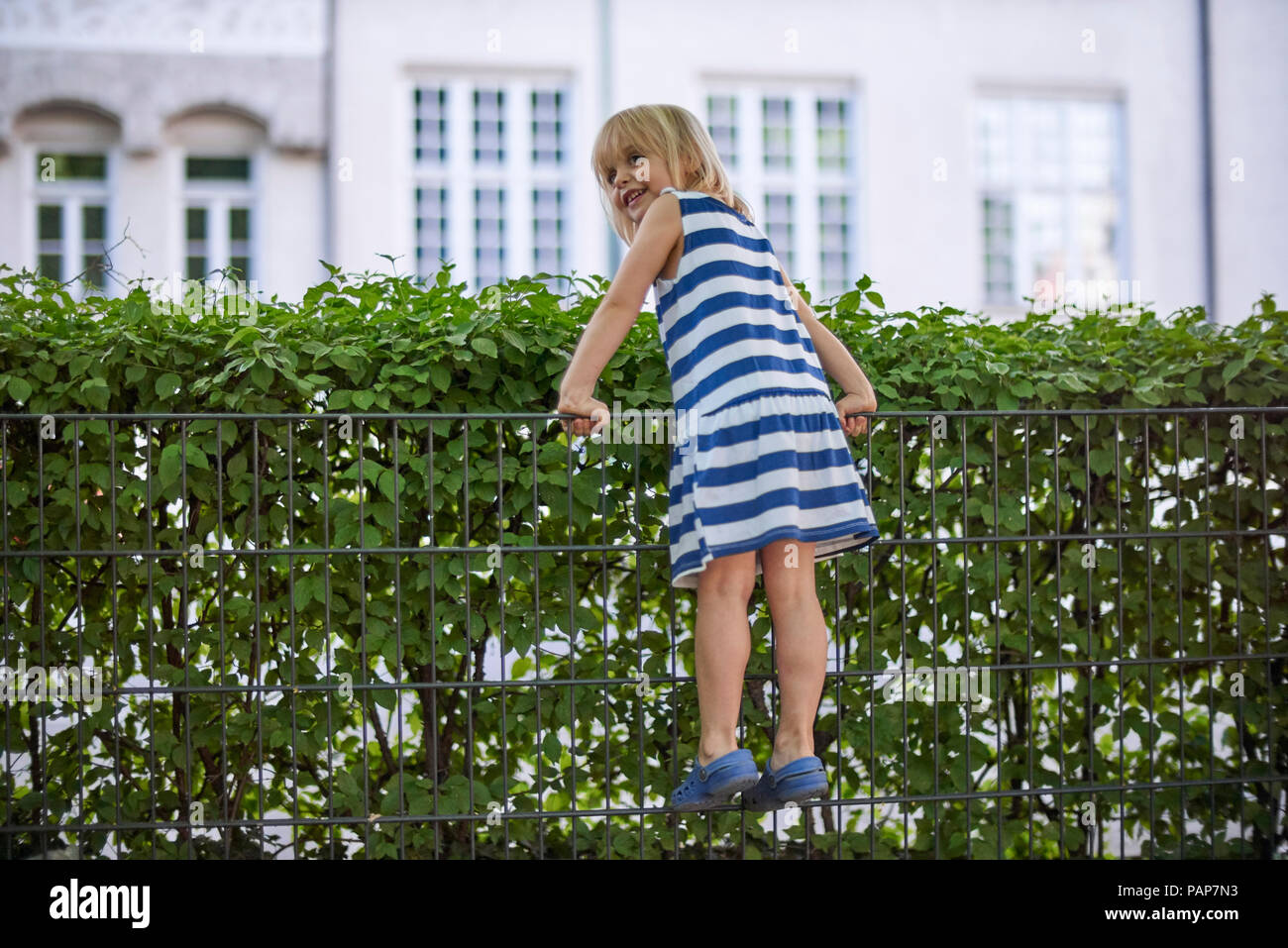 Smuling little girl climbing on fence Stock Photo Alamy