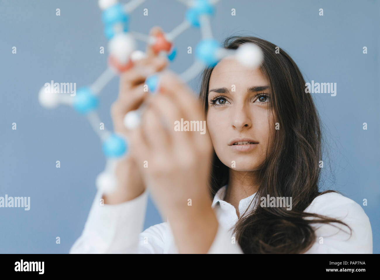 Female scientist holding molecule model, looking for solutions Stock Photo