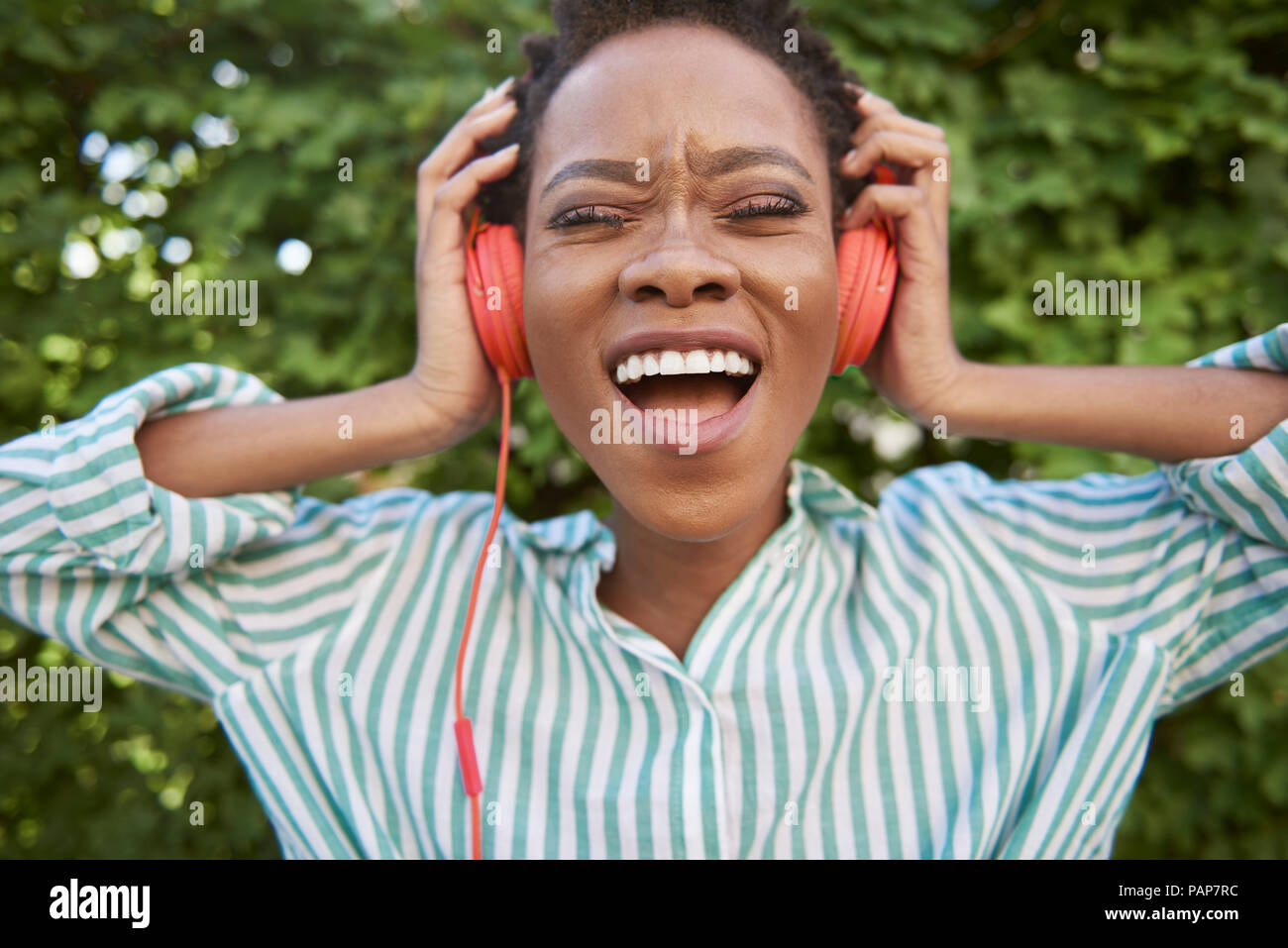 Portrait of singing young woman with headphones Stock Photo