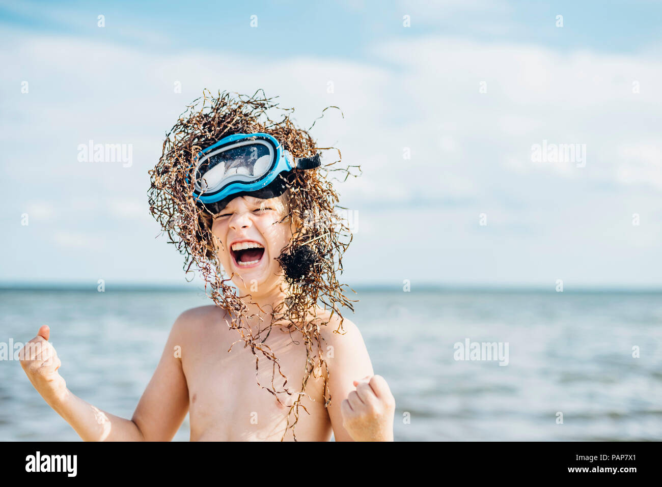 Carefree boy wearing seaweed wig on the beach Stock Photo