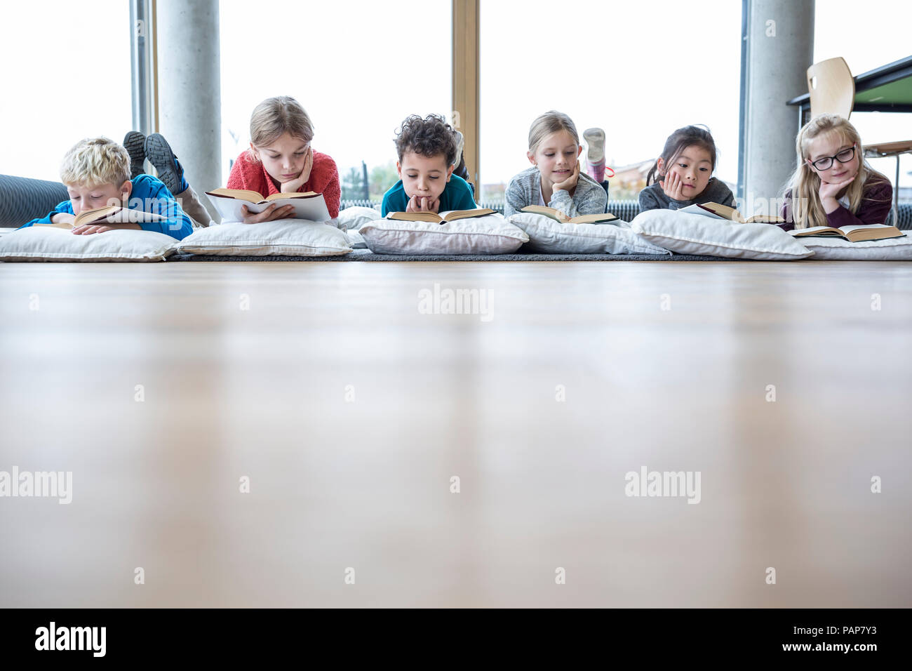 Pupils lying on the floor reading books in school break room Stock Photo