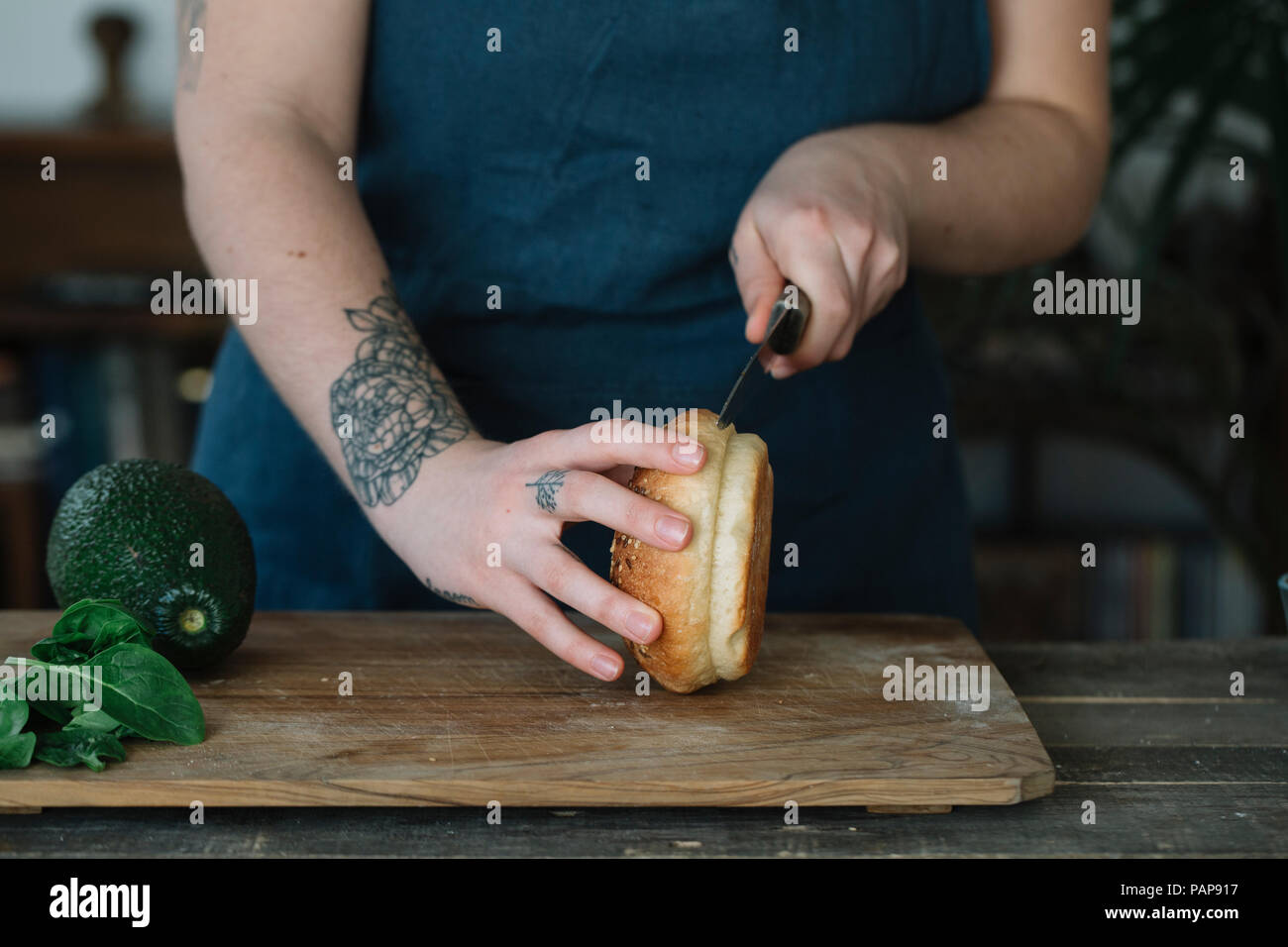 Woman preparing vegan burger, cutting bread roll Stock Photo