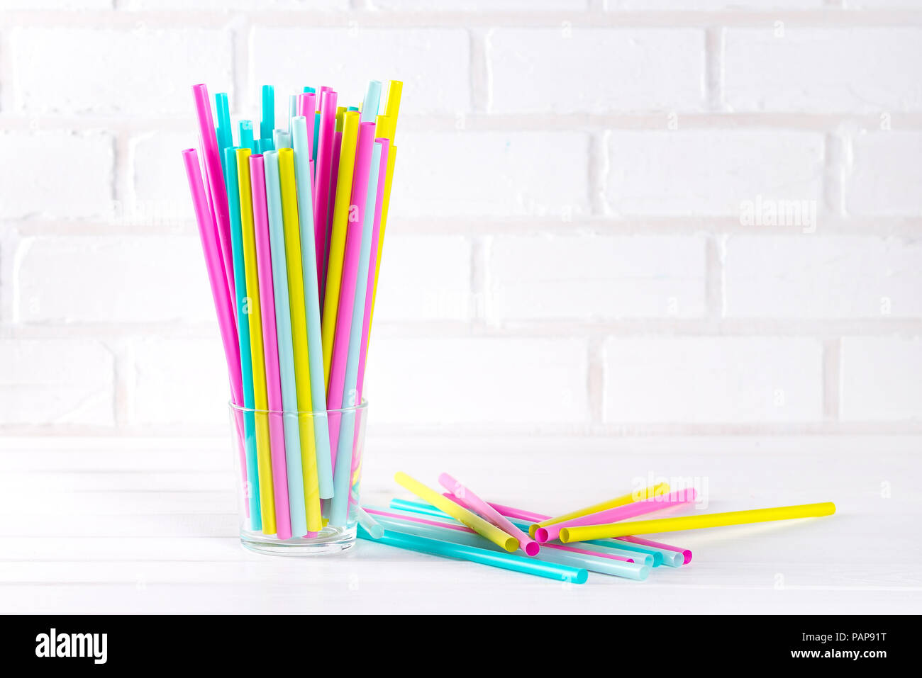 Multicolor cocktail tubes in a grass on white background. Close up. Copy space Stock Photo