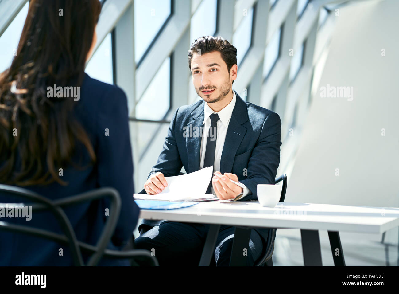 Businessman looking at businesswoman in modern office Stock Photo