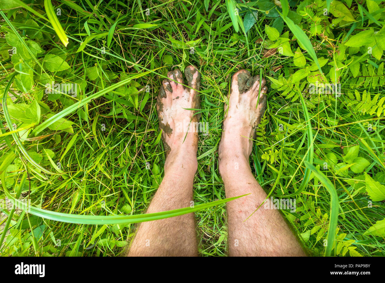 Muddy toes and feet while trekking barefoot through jungle plants in