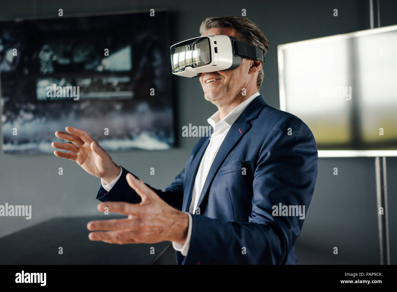 Mature businessman wearing VR glasses in office Stock Photo - Alamy