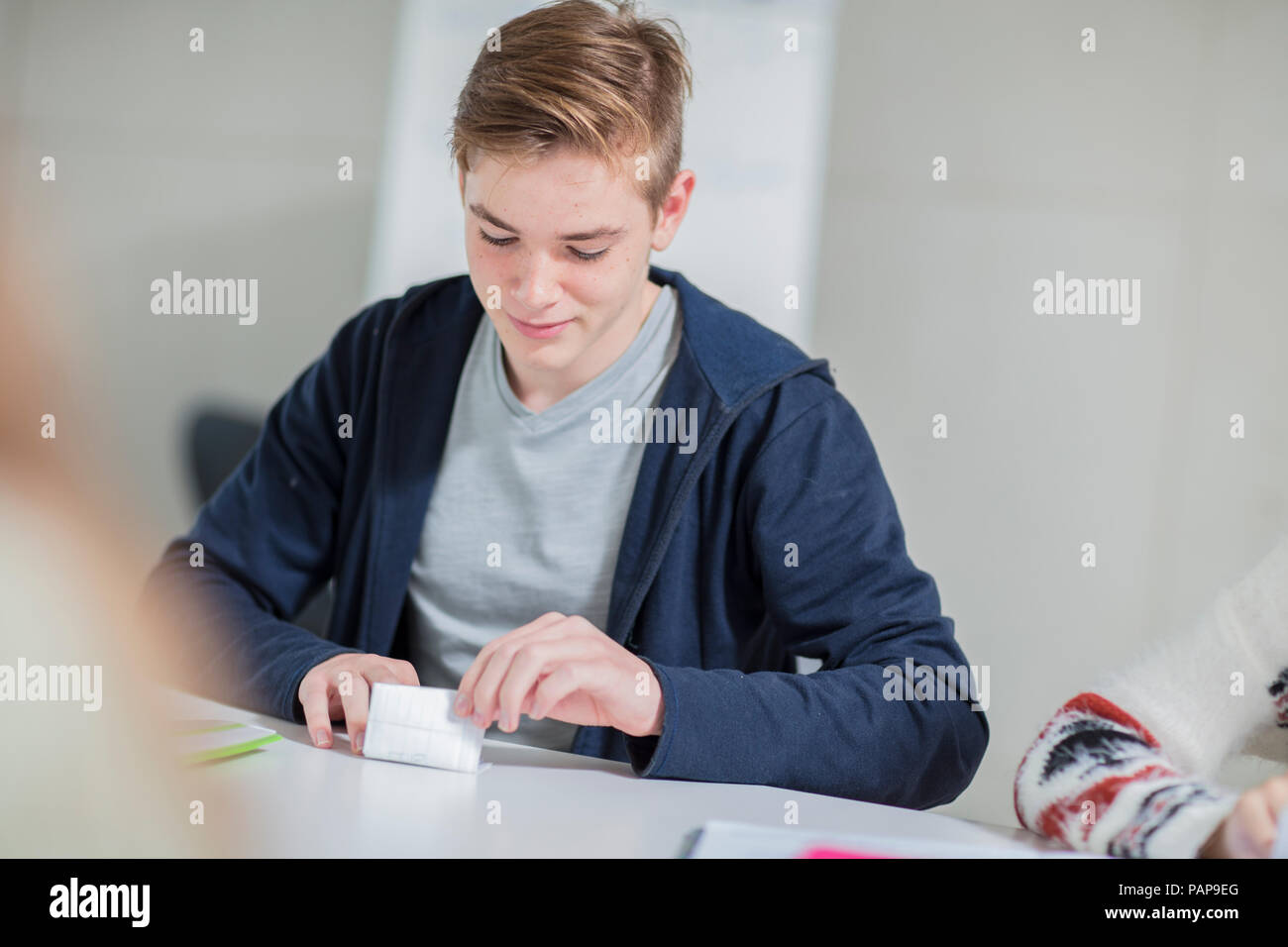 Teenage boy folding note in class Stock Photo