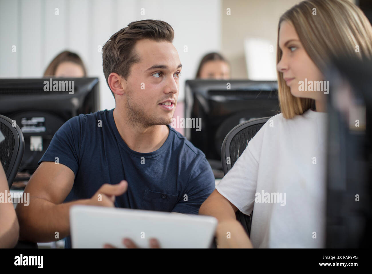 Teacher talking to student in computer class Stock Photo