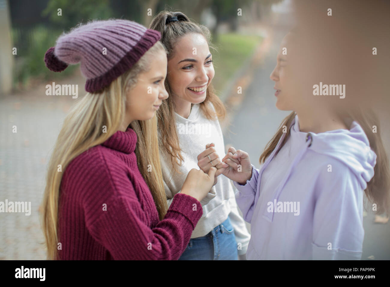 Smiling teenage girls making a pinky promise Stock Photo