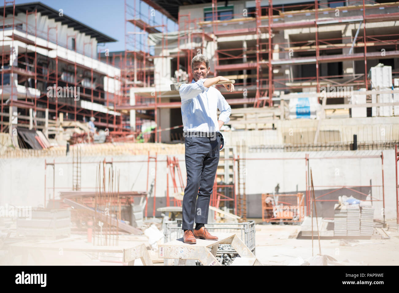 Smiling man standing on construction site holding a hammer Stock Photo ...