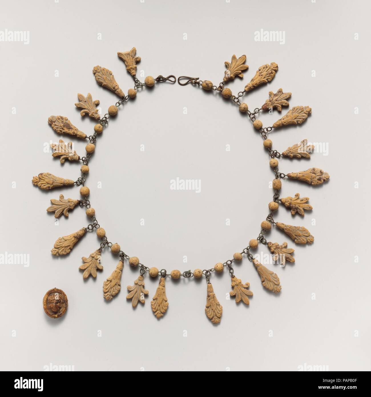 Terracotta necklace with palmette and lotus pendants. Culture: Etruscan. Dimensions: 18 1/2 in. (47 cm)  bead: 1/4 in. (0.7 cm)  largest palmette: 1 1/4 in. (3.2 cm)  smallest palmette: 1 1/16 in. (2.6 cm)  pendant: 15/16 × 3/4 × 3/8 in. (2.3 × 1.9 × 1 cm). Date: 3rd century B.C..  Terracotta jewelry represents an inexpensive substitute for pieces in precious metals. The pendants would have been produced in large numbers through the use of molds, thus reducing the cost of both labor and material. Museum: Metropolitan Museum of Art, New York, USA. Stock Photo