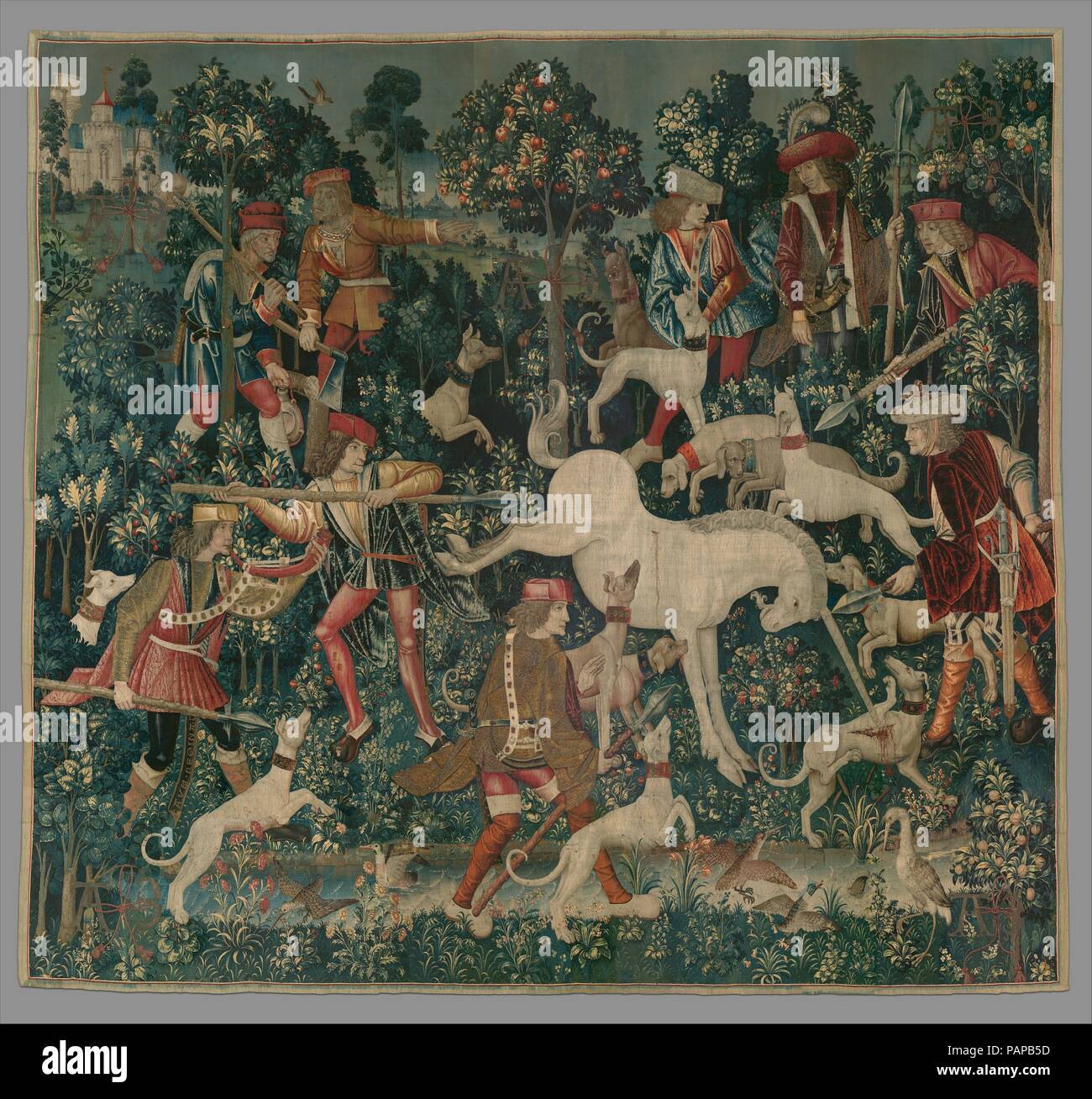 The Unicorn Defends Itself (from the Unicorn Tapestries). Culture: South Netherlandish. Dimensions: Overall: 145 x 158 in. (368.3 x 401.3cm). Date: 1495-1505.  Here the injured unicorn is being held at bay by three hunters ready to pierce him with their lances. The furious animal reacts with a gruesome attack on a greyhound before him, almost tearing the dog's body apart. The horn-blowing hunter at the lower left wears a scabbard with the inscription AVE REGINA C[OELI] (Hail, Queen of the Heavens). The huntsmen and other figures are garbed in the fashions of about the turn of the sixteenth cen Stock Photo