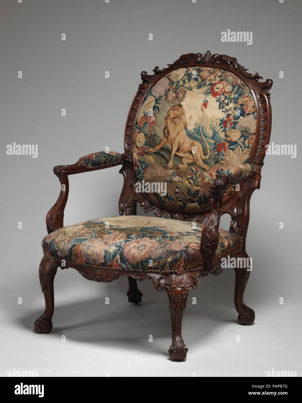 Armchair (one of four). Culture: British and French, probably Beauvais. Dimensions: Overall: 44 × 32 × 28 in. (111.8 × 81.3 × 71.1 cm). Factory: Tapestry probably woven at Royal Manufactory Beauvais 1664-1789. Date: 1755-65.  These chairs are from a set of six armchairs and two settees supplied to the third Duke of Ancaster (1714-1778) for Grimsthorpe Castle, Lincolnshire. The set was originally partially gilt and upholstered with Gobelins coverings (now Rijksmuseum, Amsterdam) after designs by Francois Boucher. The present coverings were applied between 1934 and 1858. Museum: Metropolitan Mus Stock Photo