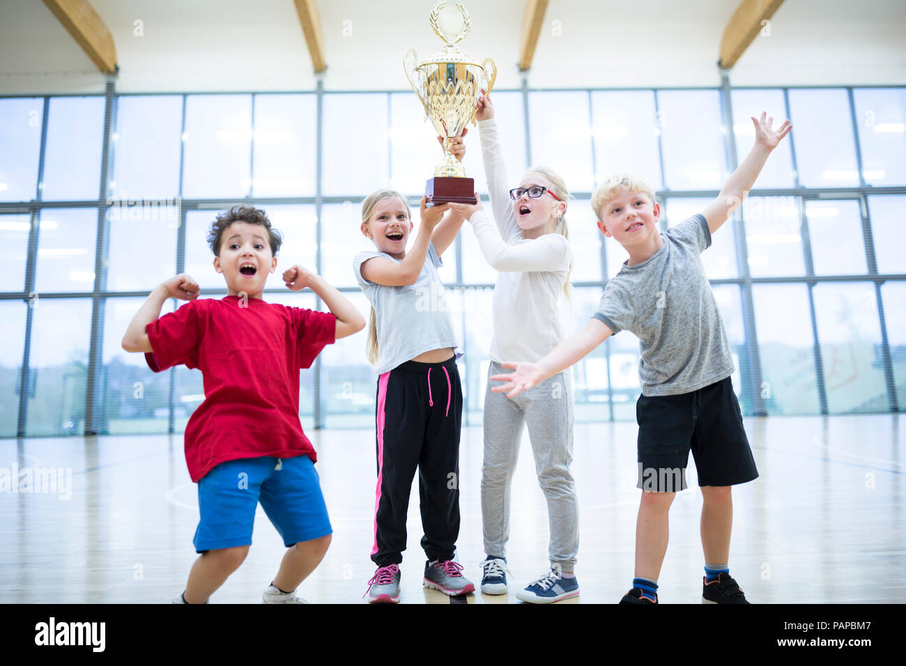 Happy pupils holding trophy in gym Stock Photo