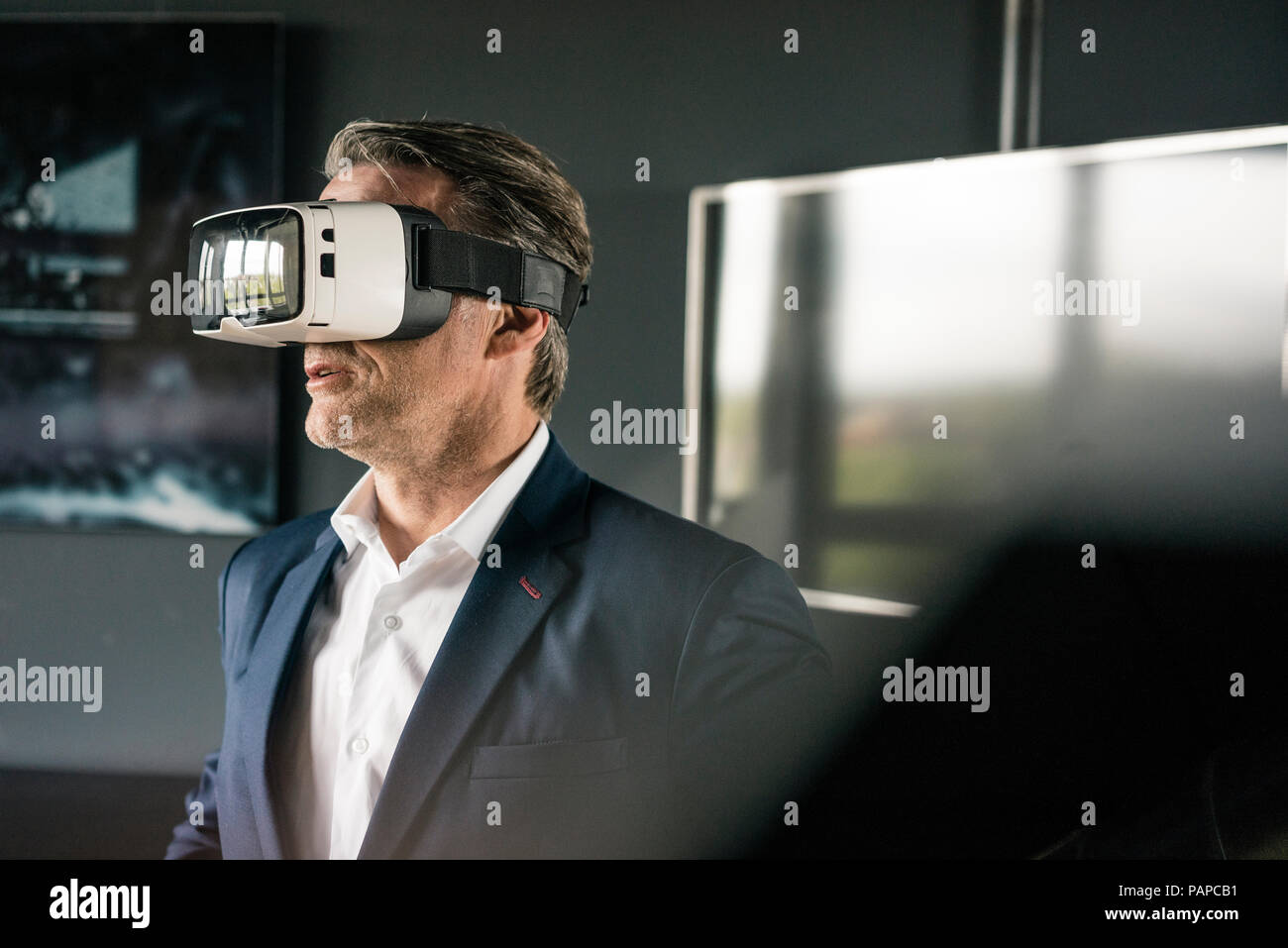 Mature businessman wearing VR glasses in office Stock Photo - Alamy