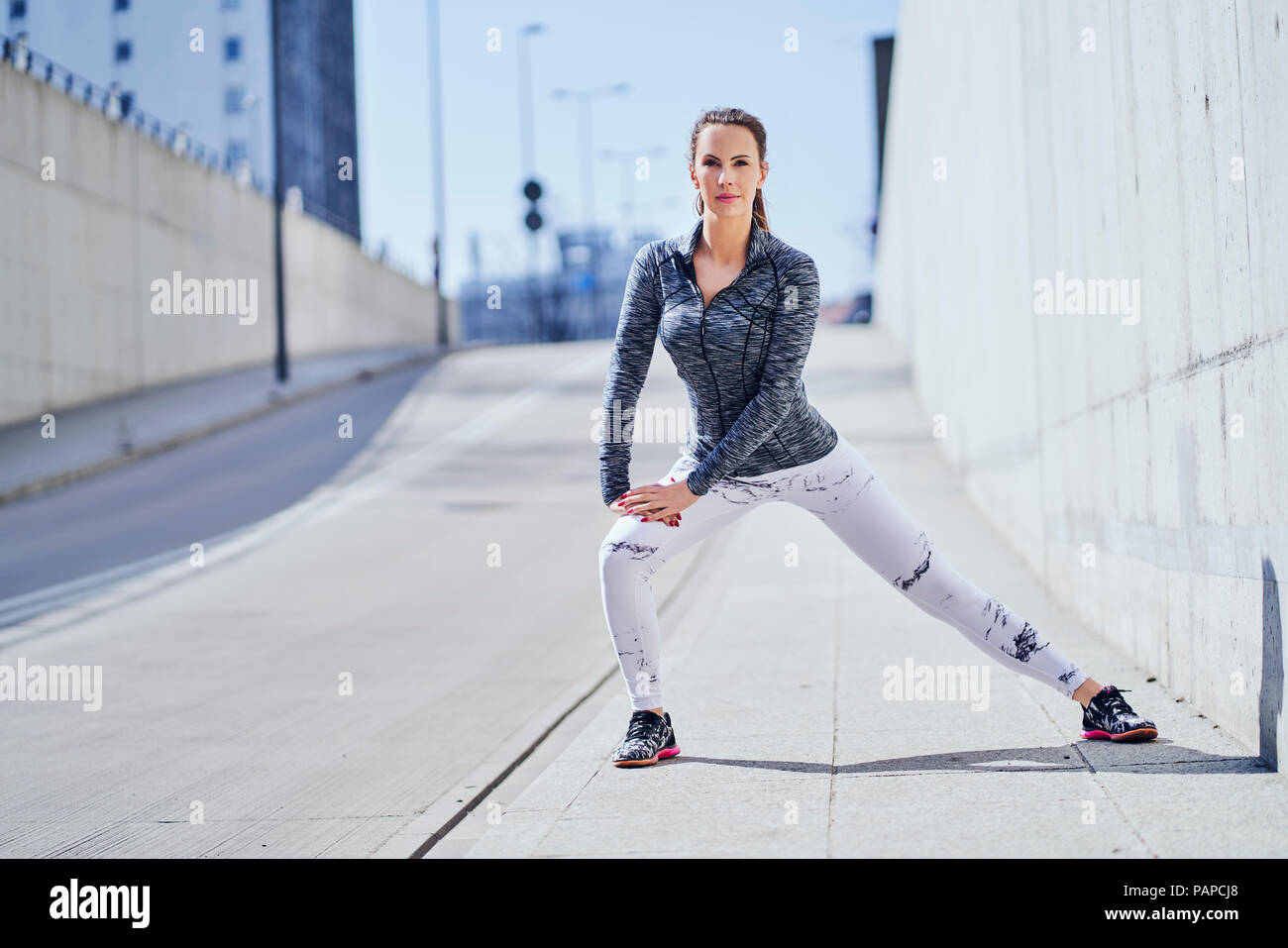 Female runner stretching legs during urban workout Stock Photo