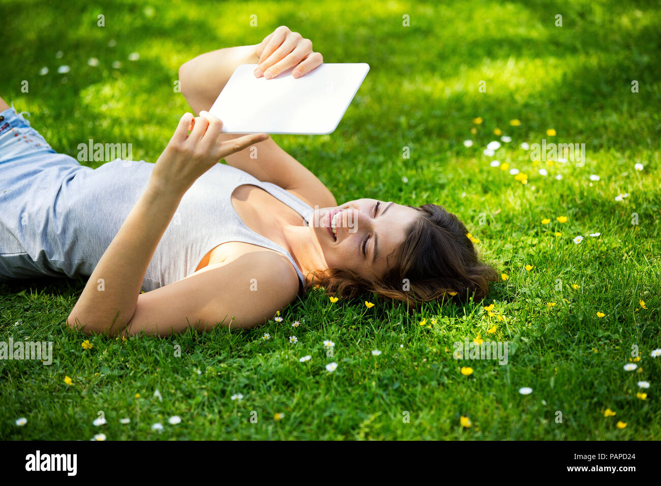 Young woman lying on meadow, using tablet Stock Photo