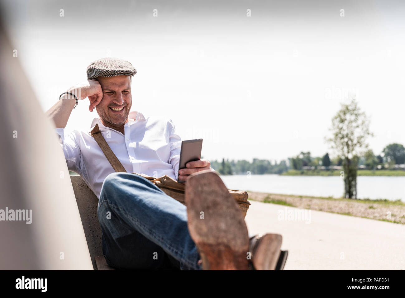 Mature man using smartphone on bench Stock Photo
