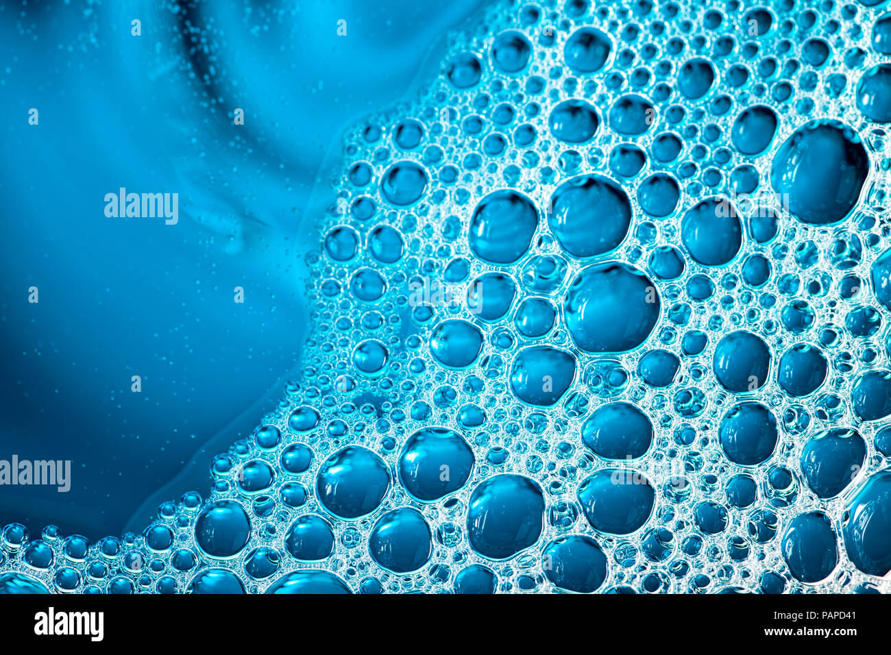 Blue bubbles. Selective focus aesthetic liquid background image. Abstract chaotic pattern of surface tension bubble froth in macro close-up. Stock Photo