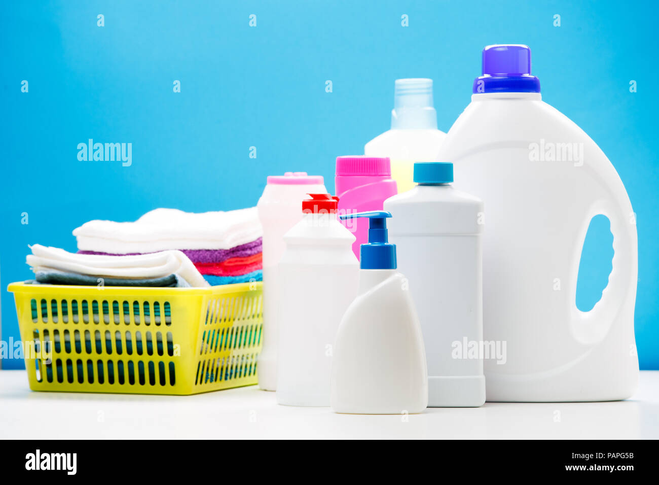 https://c8.alamy.com/comp/PAPG5B/photo-of-different-bottles-of-cleaning-products-and-colored-towels-in-basket-isolated-on-blue-background-place-for-inscription-PAPG5B.jpg