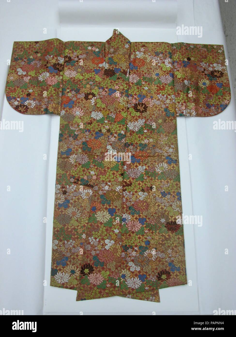 Noh Robe (Karaori) with Autumn Flowers and Grasses. Culture: Japan. Dimensions: Overall (with collar): H. 69 in. (175.3 cm); W. 58 in. (147.3 cm). Date: first half of the 19th century.  Karaori, literally 'Chinese Weave,' is a stiff brocade technique that employs a uniform direction of weft in which long stitches of glossed silk threads are floated over an unglossed silk twill ground, while foil-covered flat threads are bound close to the twill ground weave. The stiff karaori brocade does not drape easily, but it creates an angular effect, helping to evoke the spirit of a former noblewoman. Th Stock Photo