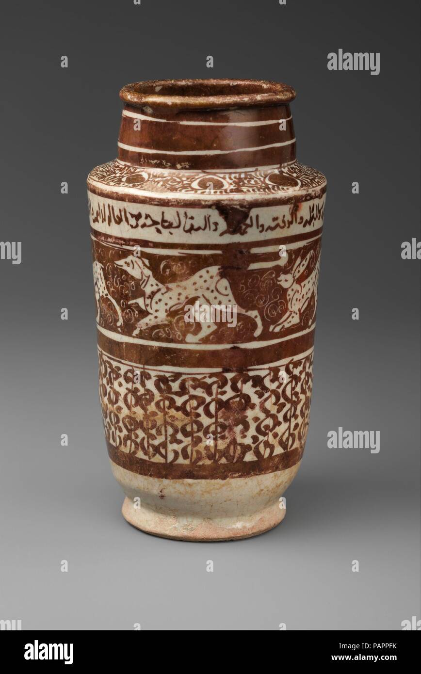 Apothecary Jar with Running Hares and a Dog. Dimensions: H. 7 1/4 in. (18.4 cm)  Diam. 4 in. (10.2 cm). Date: 12th century.  This jar was used to store solid substances (dried herbs, roots, bark, seeds, and fruit, or salts, minerals, and metals) most likely employed in the preparation of drugs or home remedies. The iconography is not directly connected to the jar's function, but the chasing animals and the Arabic benedictory words addressed to the owner convey an overall propitious symbolism. For their cleverness and speed the hare seems to have been regarded as especially auspicious. Museum:  Stock Photo
