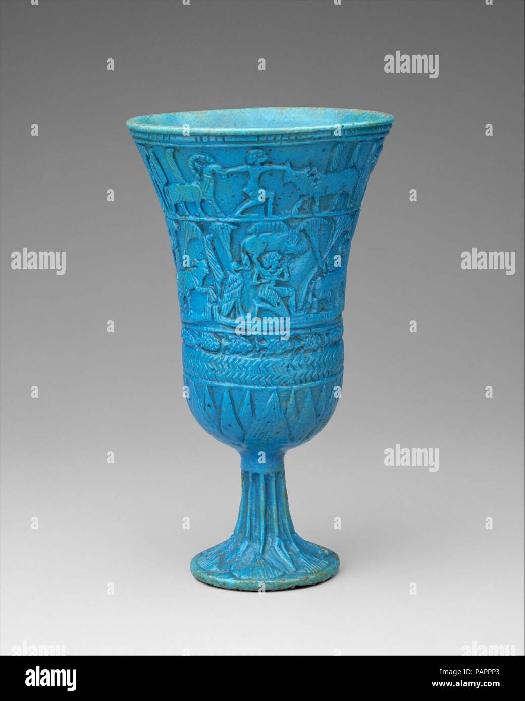 Lotiform Chalice. Dimensions: h. 14.5 cm (5 11/16 in). Dynasty: Dynasty 22-25. Date: ca. 945-664 B.C..  The fragrant blossom of the blue lotus is a common motif in all forms of Egyptian art. Because it opened its petals to the sun each morning, the flower became a symbol of creation and rebirth. During the Third Intermediate Period, faience chalices derived from the shape of the blossom and other faience delicacies were decorated with relief scenes evoking a constellation of myths having to do with the birth of the king as child of the sun god out of the watery marsh environment, and thus the  Stock Photo