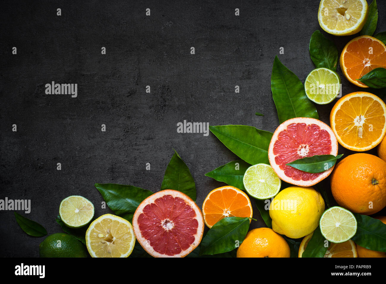Fresh citrus fruit assortment. Whole and sliced citrus fruit on black