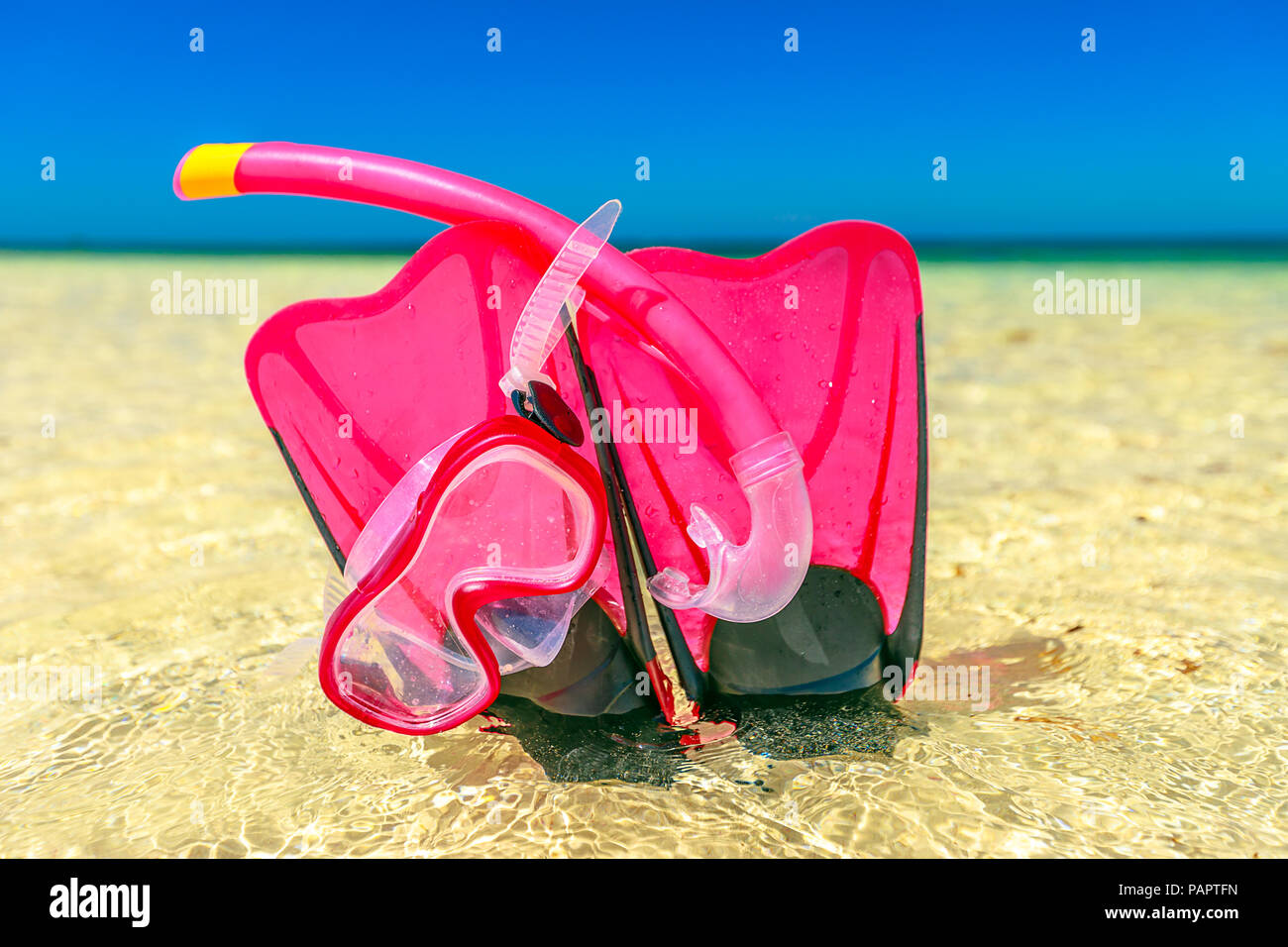 Close-up of scuba mask with fins in pink color on the sand of Hangover Bay in Nambung National Park, Western Australia. Blue sky. Summer equipment for snorkeling. Stock Photo