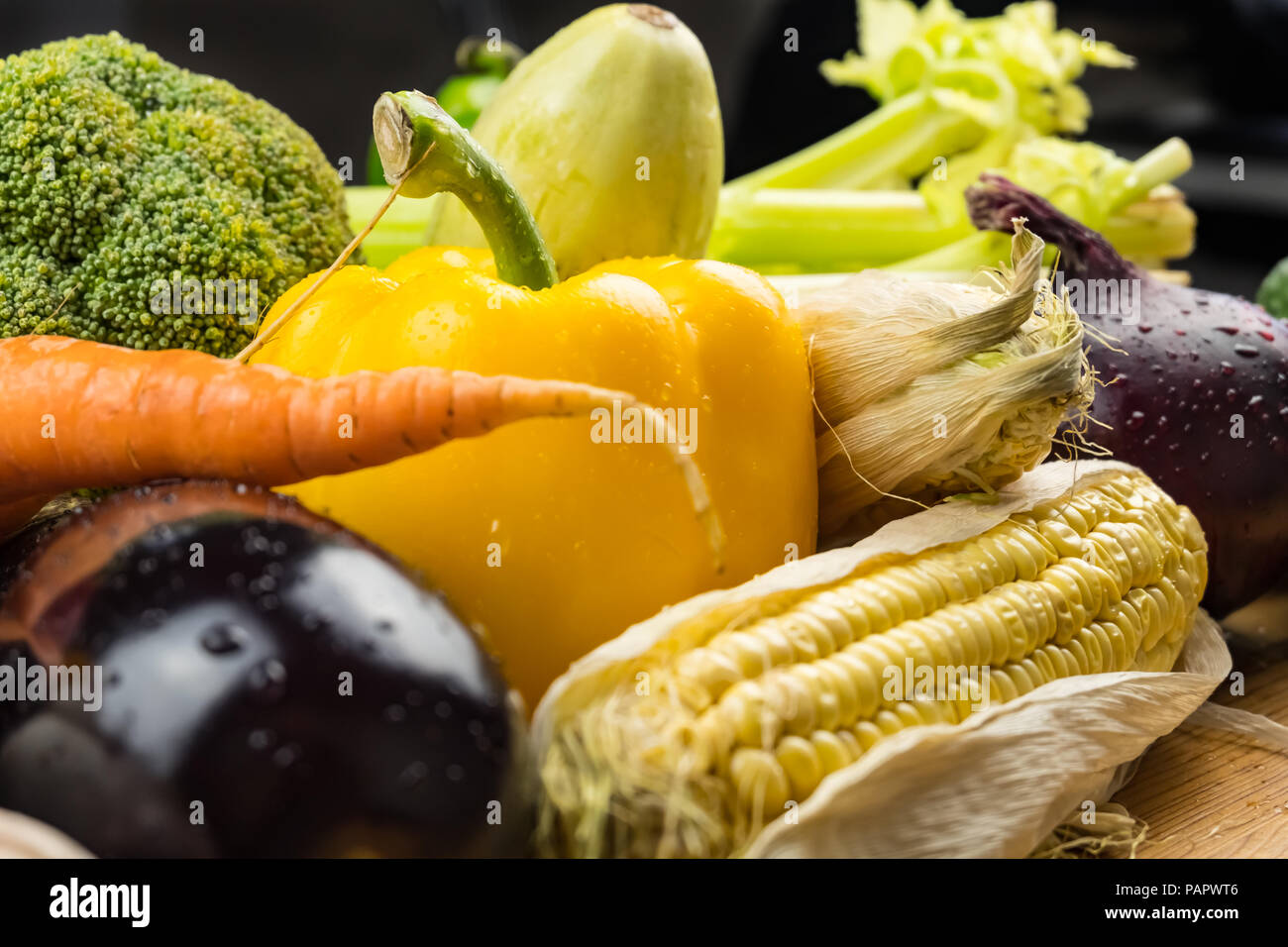 Close-up of fresh organic vegetables on rustic wood table. Locally grown bell pepper, corn and other natural vegan food laying on table Stock Photo