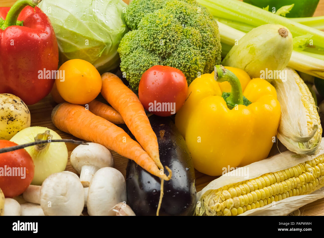 Close-up top view image of fresh organic vegetables. Locally grown bell pepper, corn, carrot, mushrooms and other natural vegan food laying on table. Stock Photo