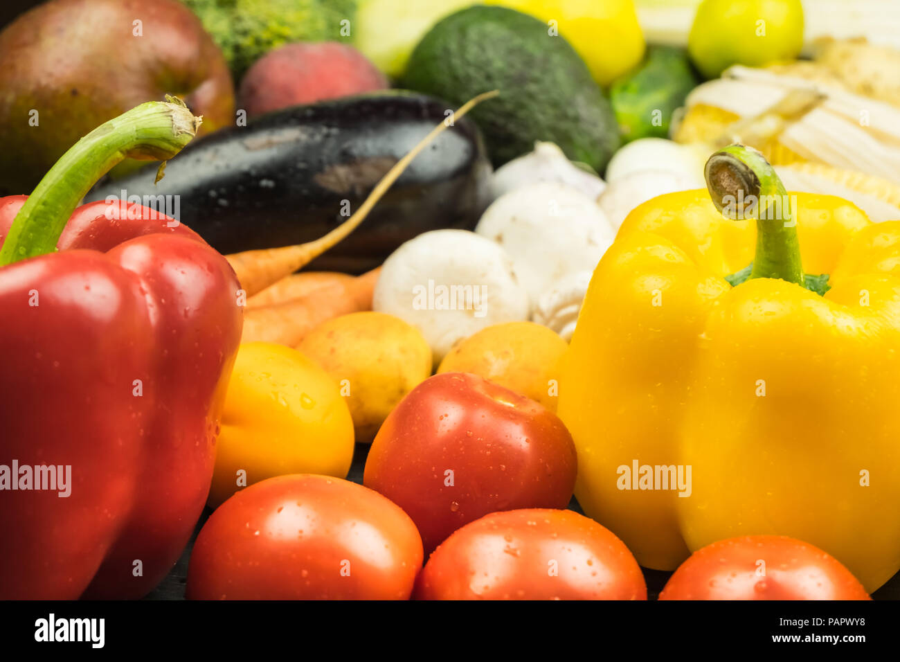 Close-up view of fresh organic bell peppers, tomatoes and other vegetables. Locally grown natural vegan food laying on table. Stock Photo