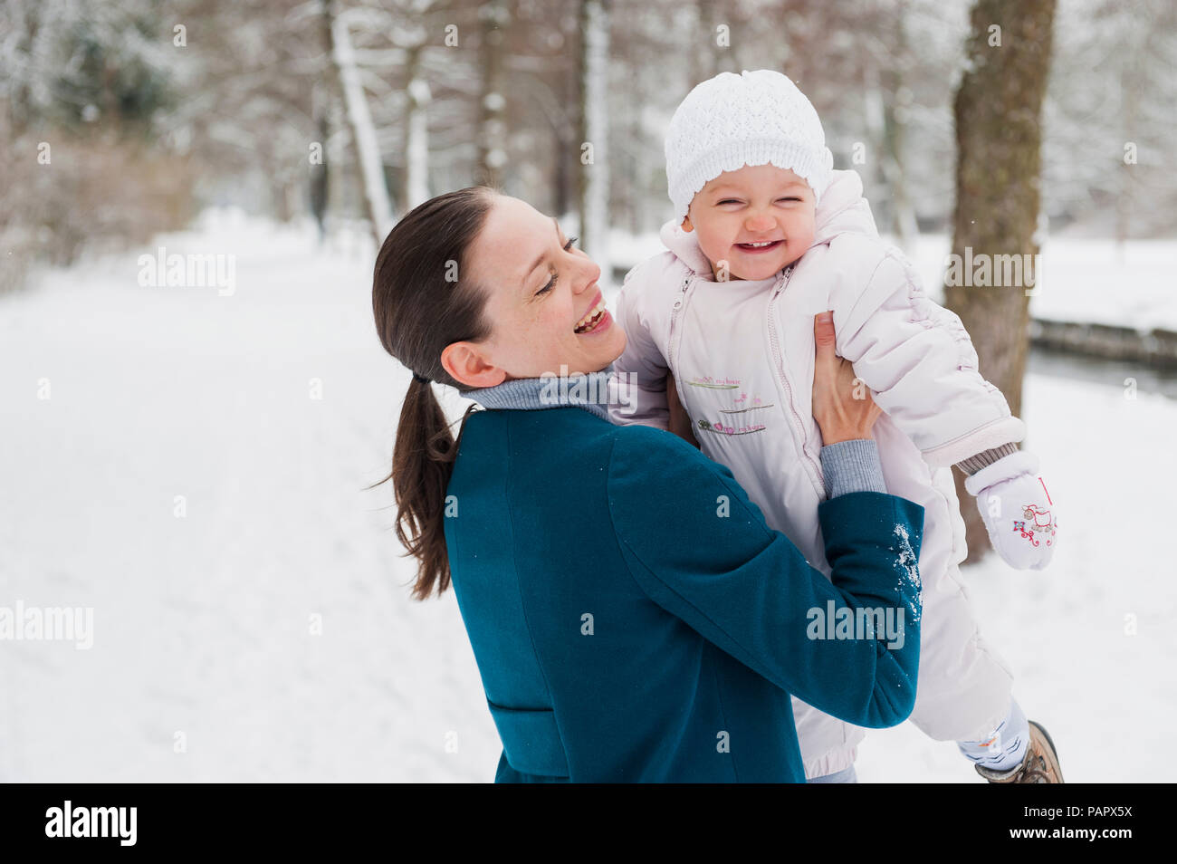 Portrait of happy baby girl having fun with her mother in snow-covered landscape Stock Photo
