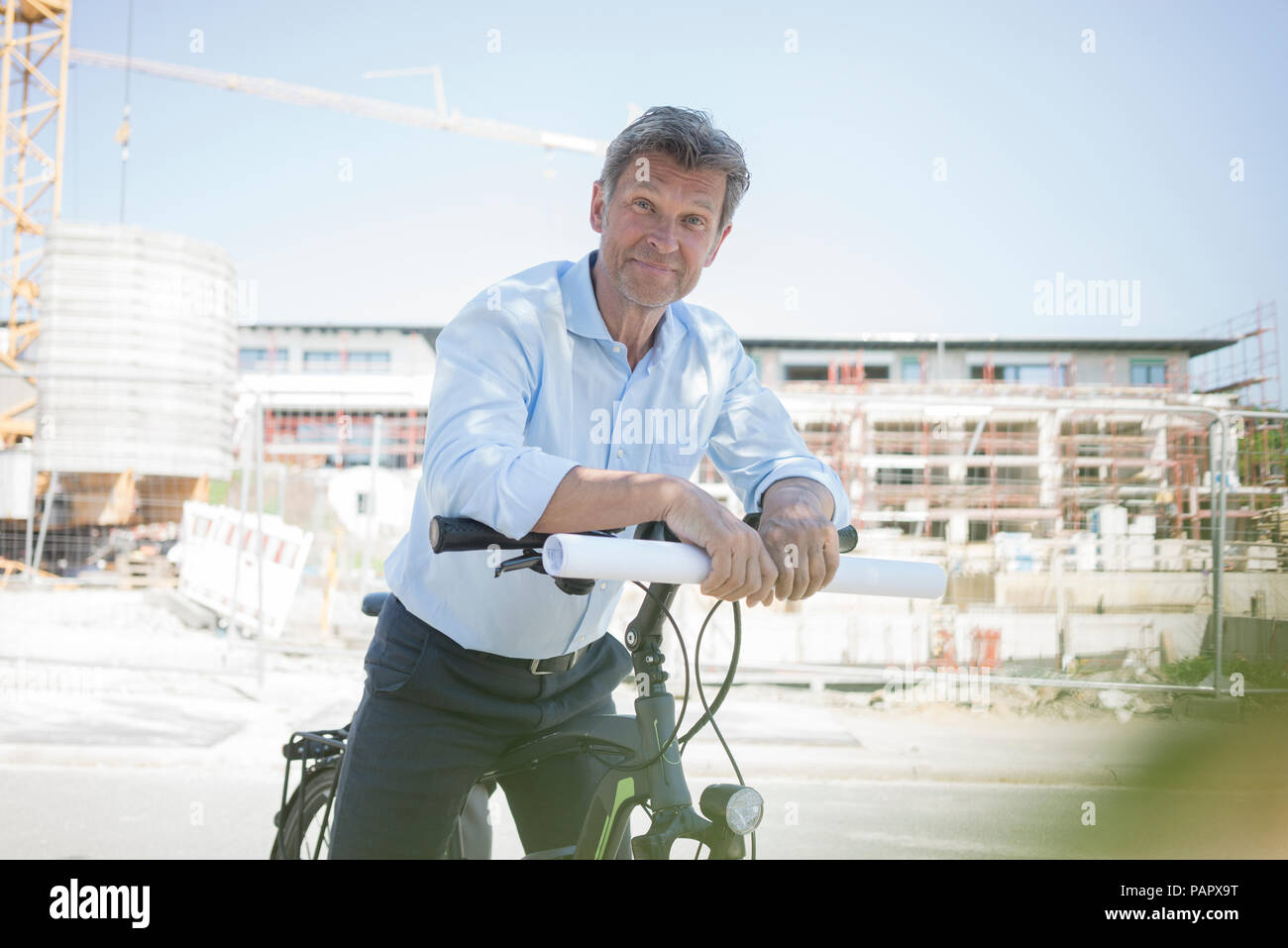 Portrait of man with e-bike on construction site Stock Photo