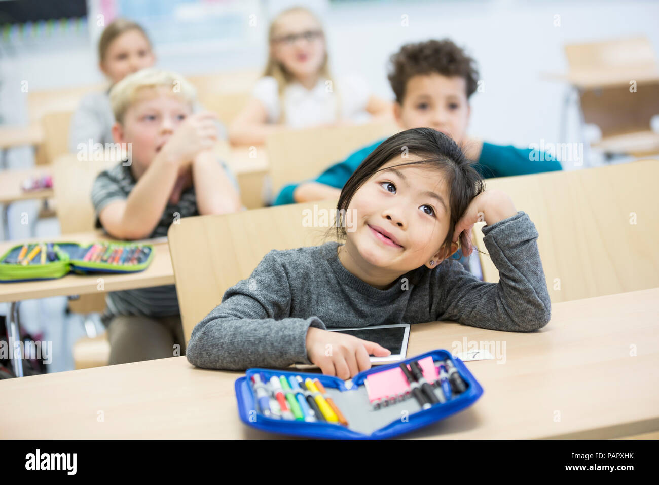 Portrait of schoolgirl with classmates in class Stock Photo