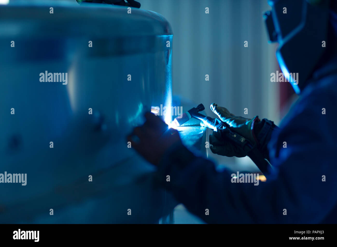 Welder in industrial plant welding tanks Stock Photo