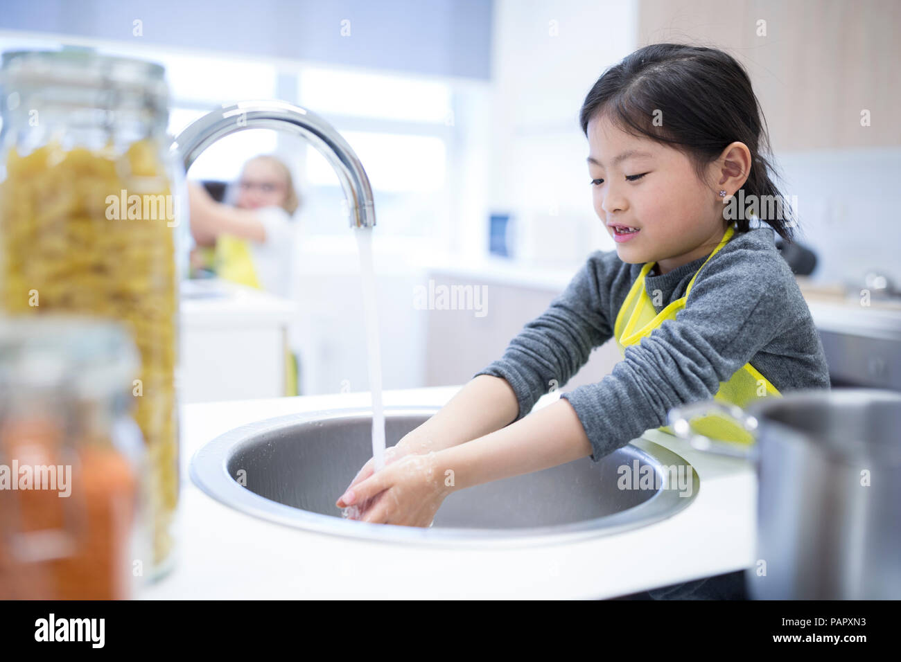 Schoolgirl washing her hands in cooking class Stock Photo