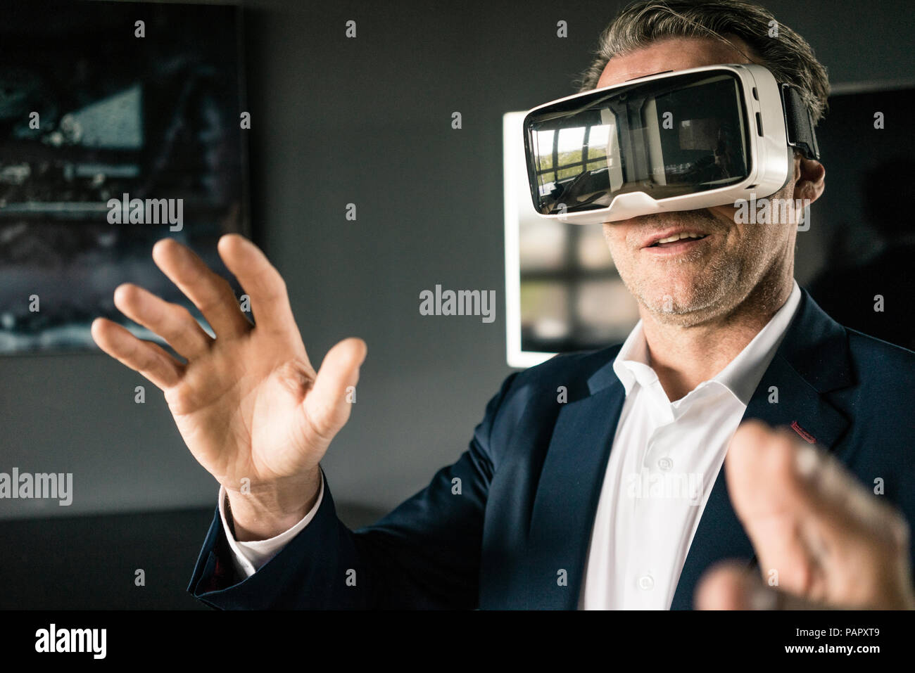 Mature businessman wearing VR glasses in office Stock Photo - Alamy