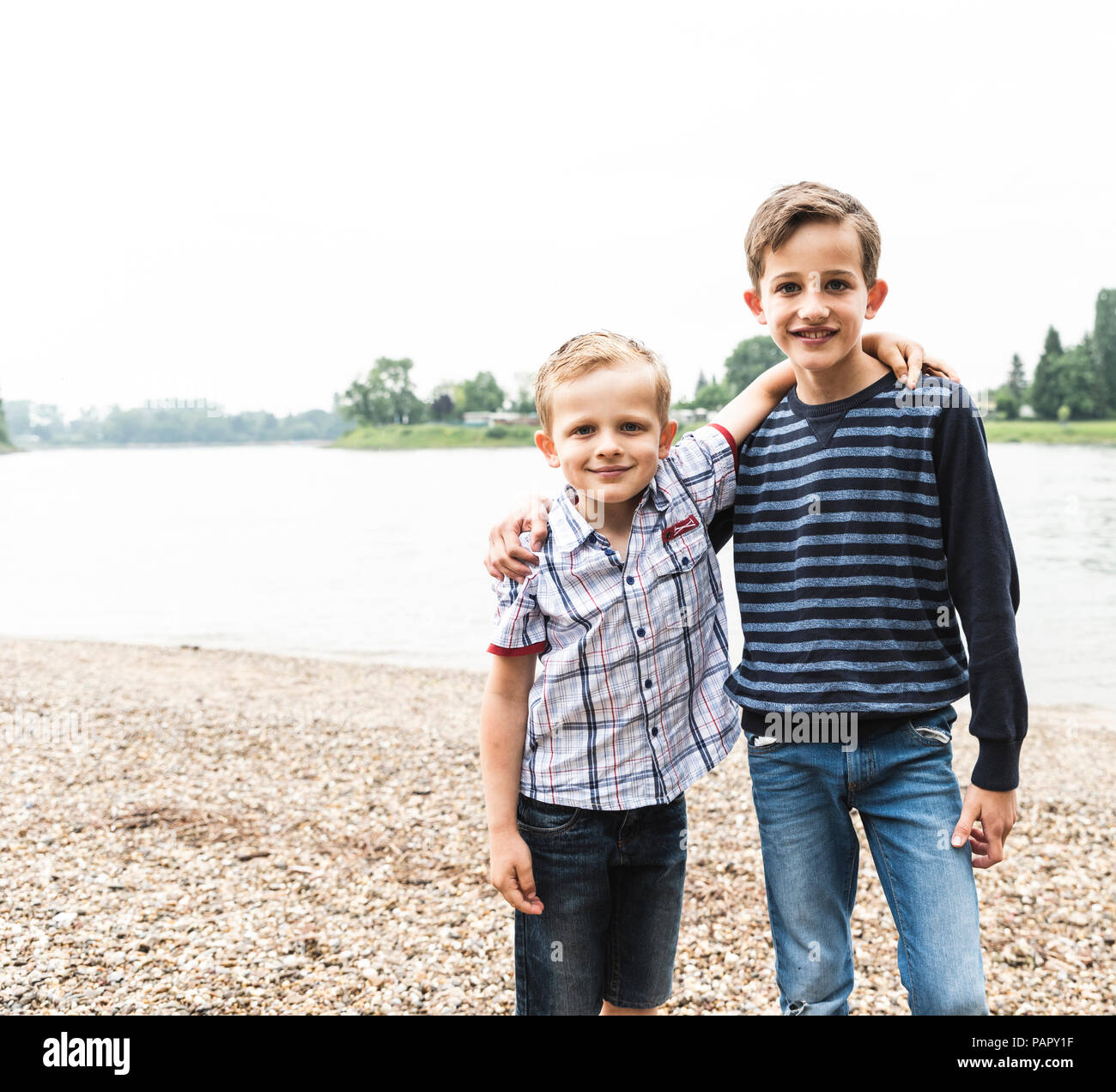 Portrait of two smiling boys embracing at the riverside Stock Photo - Alamy
