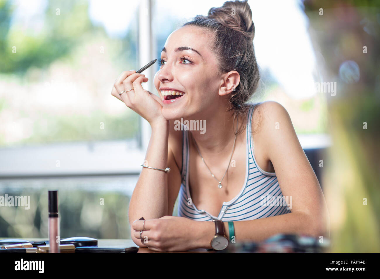Happy teenage girl applying makeup Stock Photo