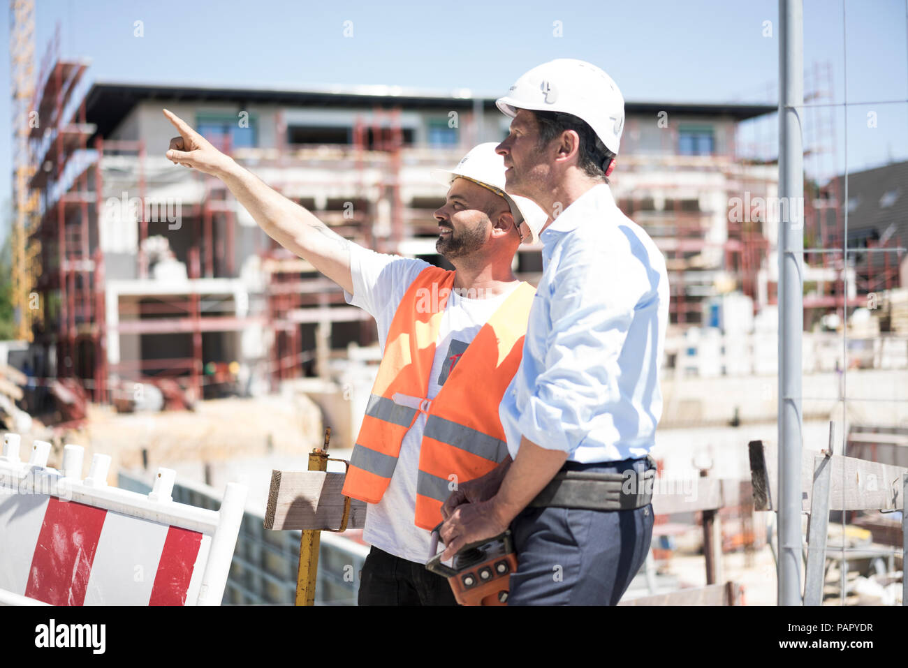 Construction worker talking to man on construction site Stock Photo - Alamy