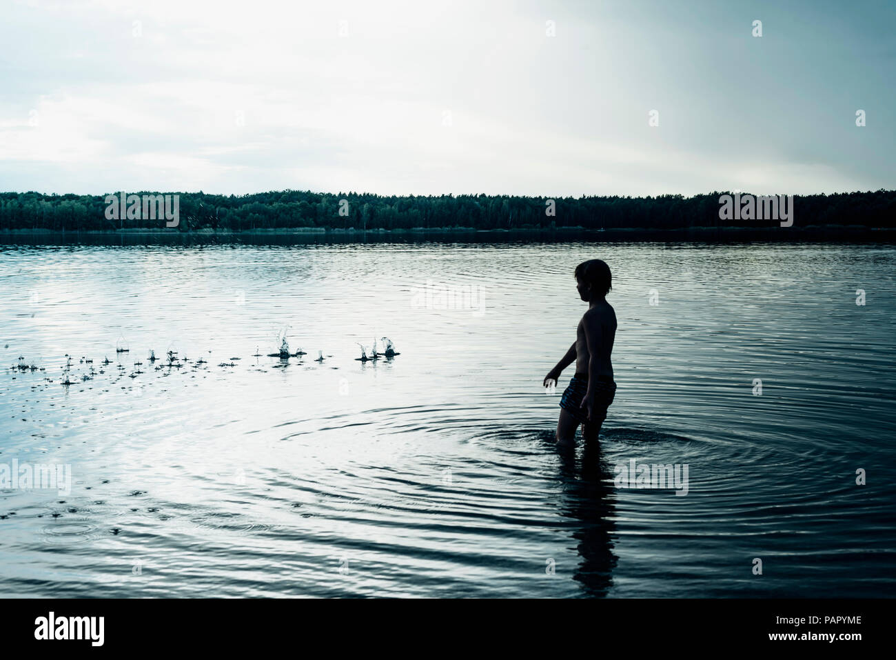 Boy in a lake at dusk Stock Photo