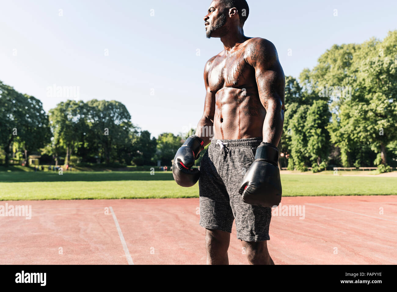 Young Afro-American man training boxing on sports field, outdoors Stock Photo