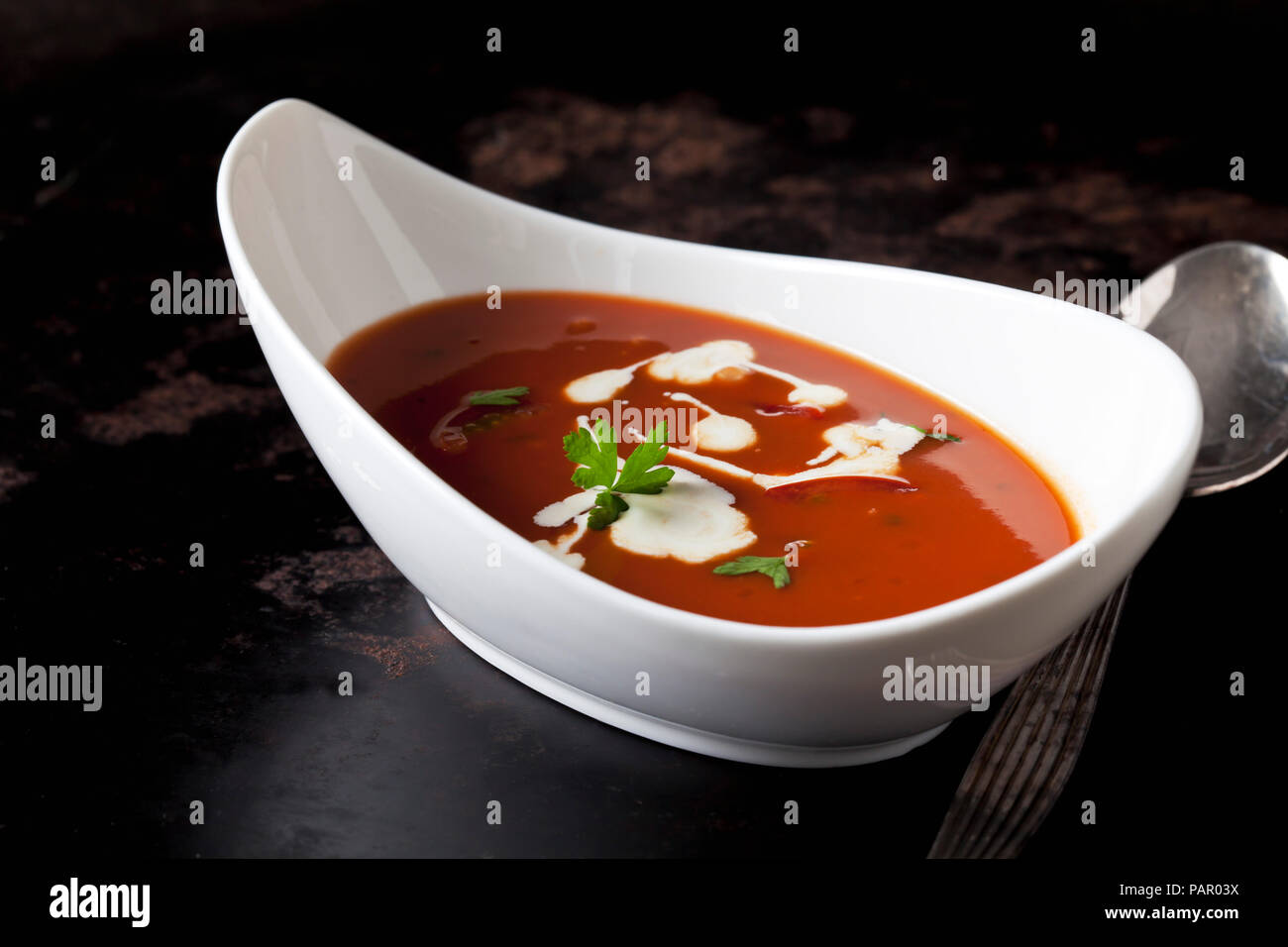 Bowl of tomato cream soup garnished with cream and parsley Stock Photo