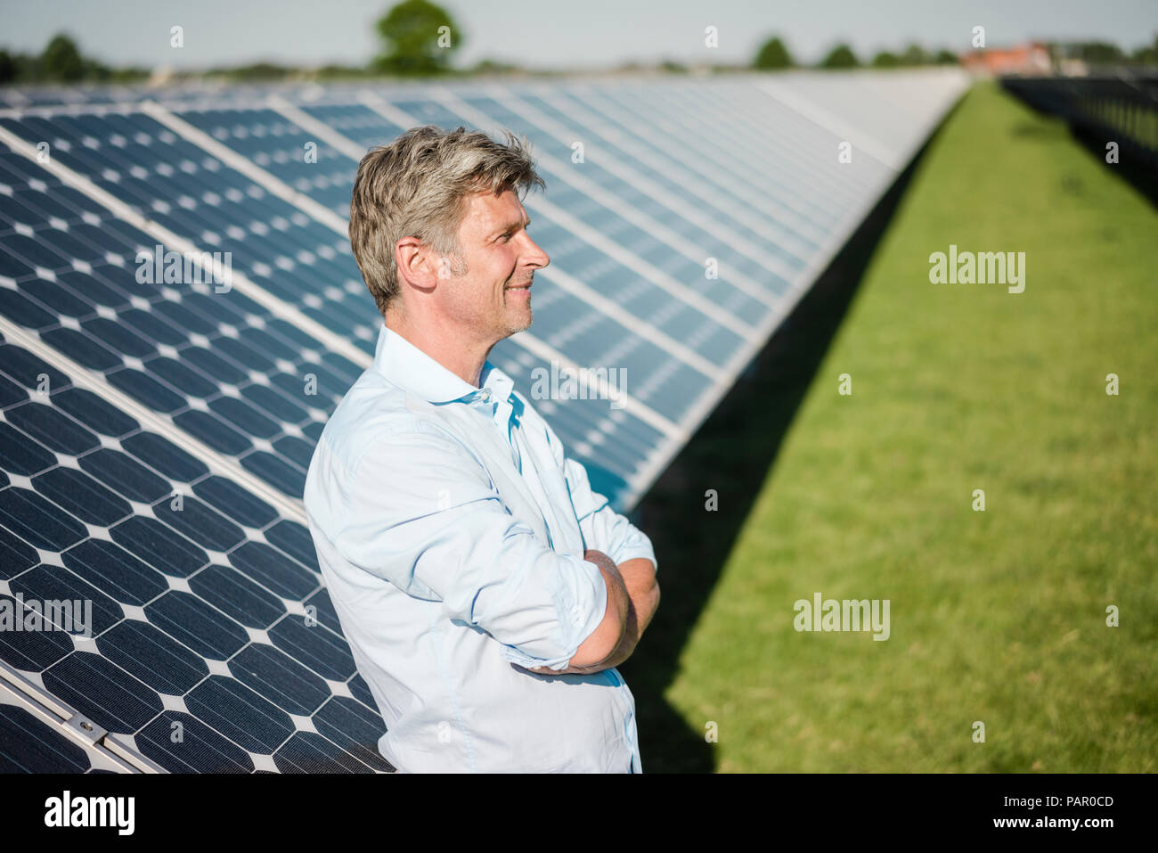 Smiling mature man standing in solar plant Stock Photo