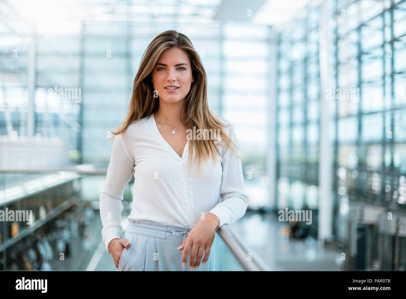 Portrait of smiling young woman standing at railing Stock Photo