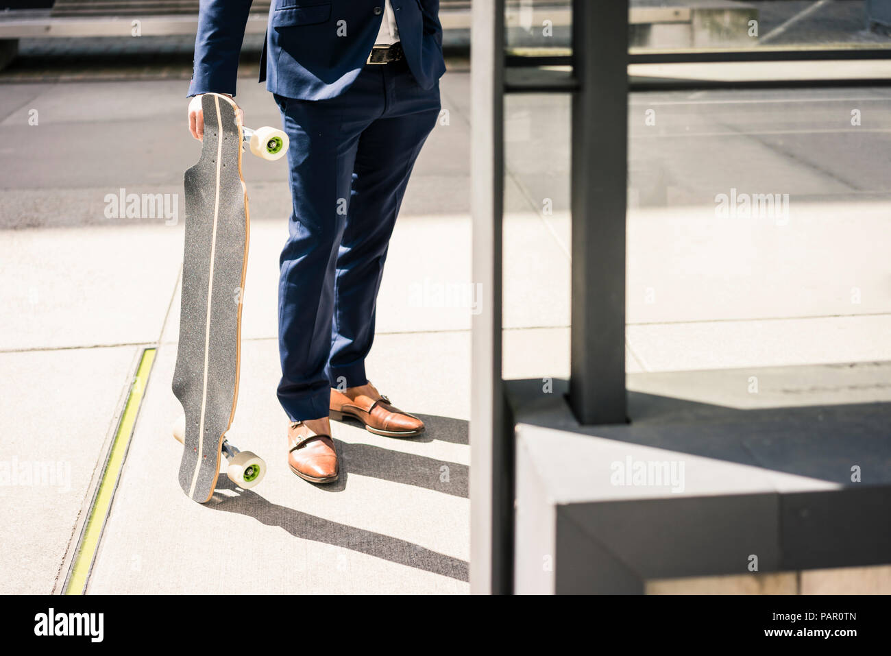 Businessman holding longboard outdoors Stock Photo