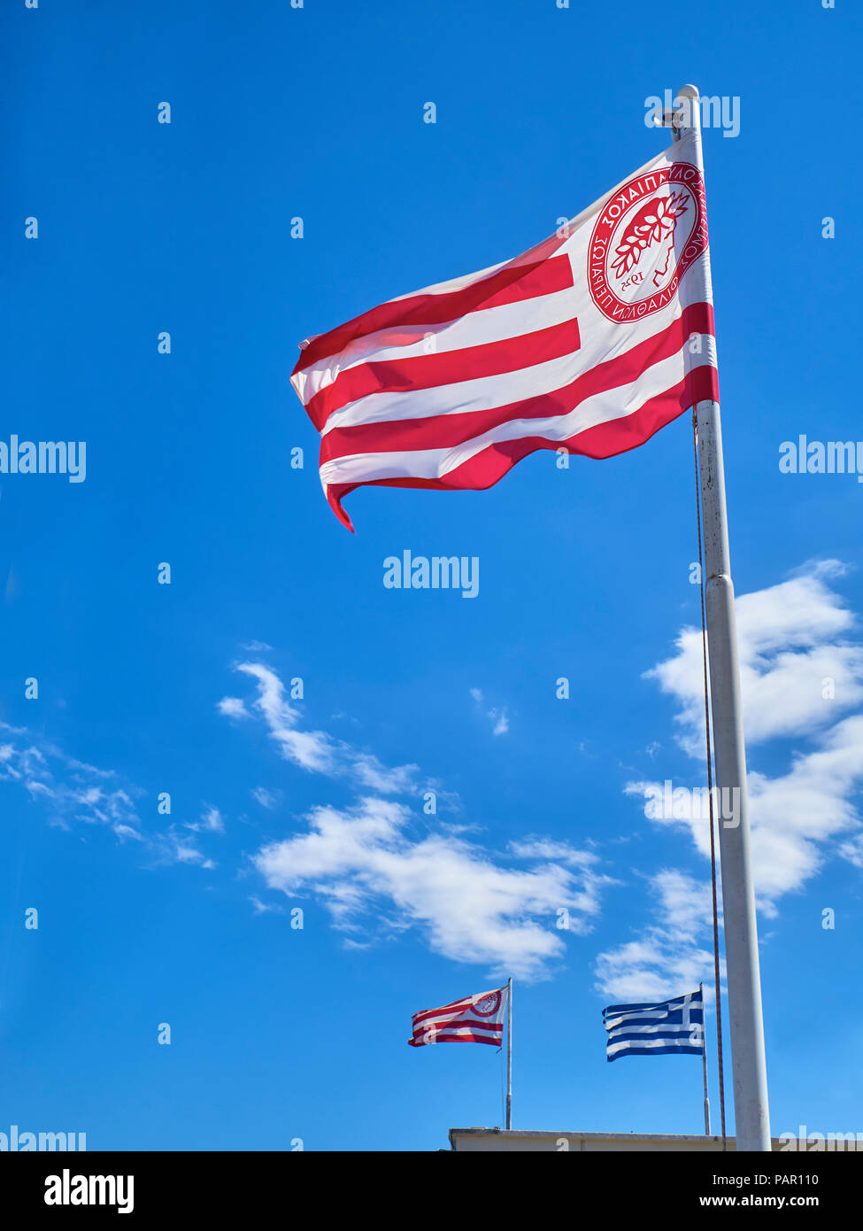 Flags of Olympiacos Football Club team and Greece waving on a blue sky. Stock Photo
